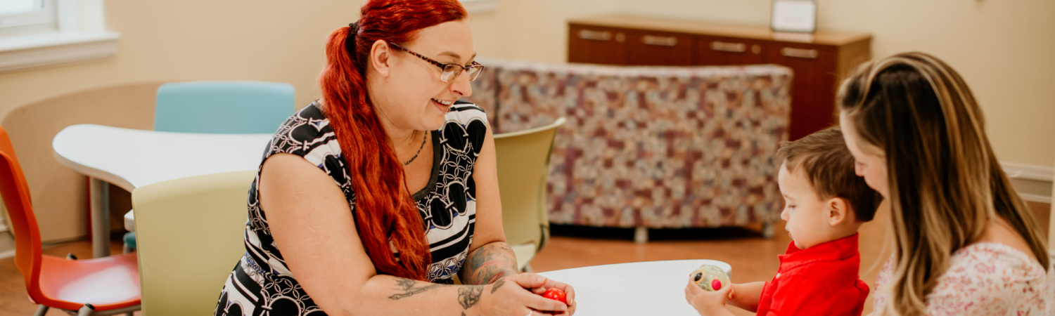 therapist seated at a table talking with a parent and her child