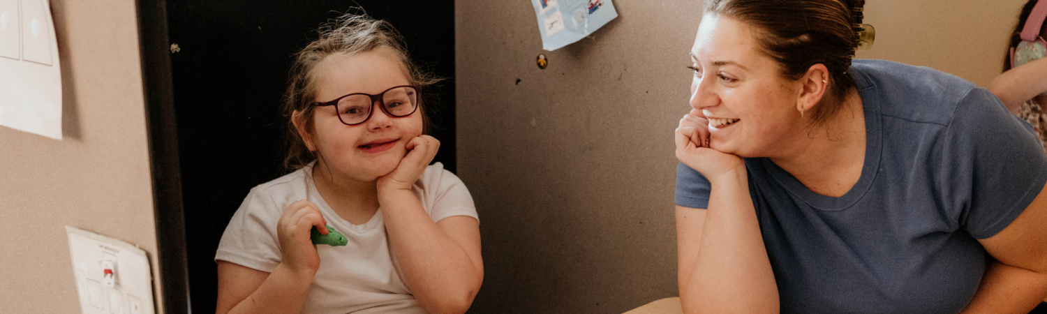 student with special needs smiling alongside her teacher