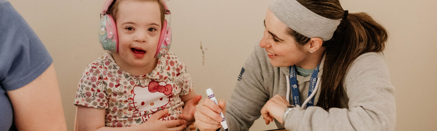 a special education teacher is shown smiling with her student at their desk