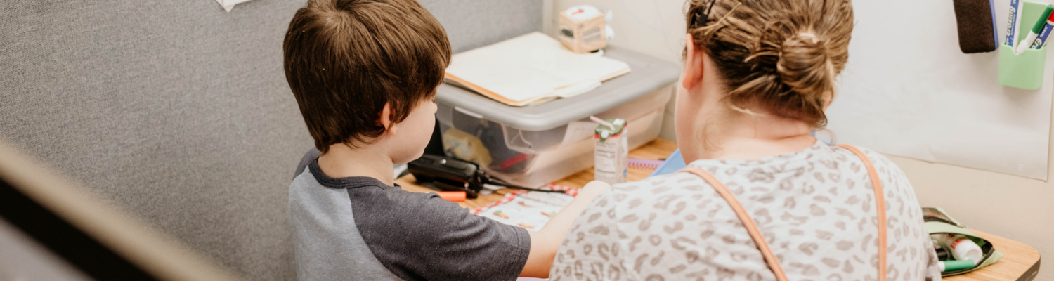 special education therapist seen working with a student at his desk