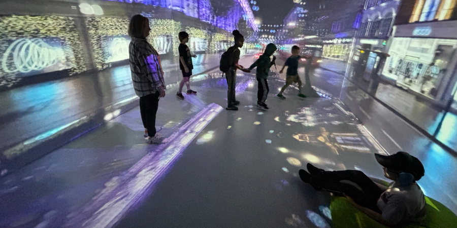 Students pictured inside of the Immersive Reality classroom interacting with a virtual reality scene.