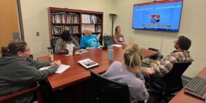 educational consultant pictured seated around a conference table with other educators sharing professional development training